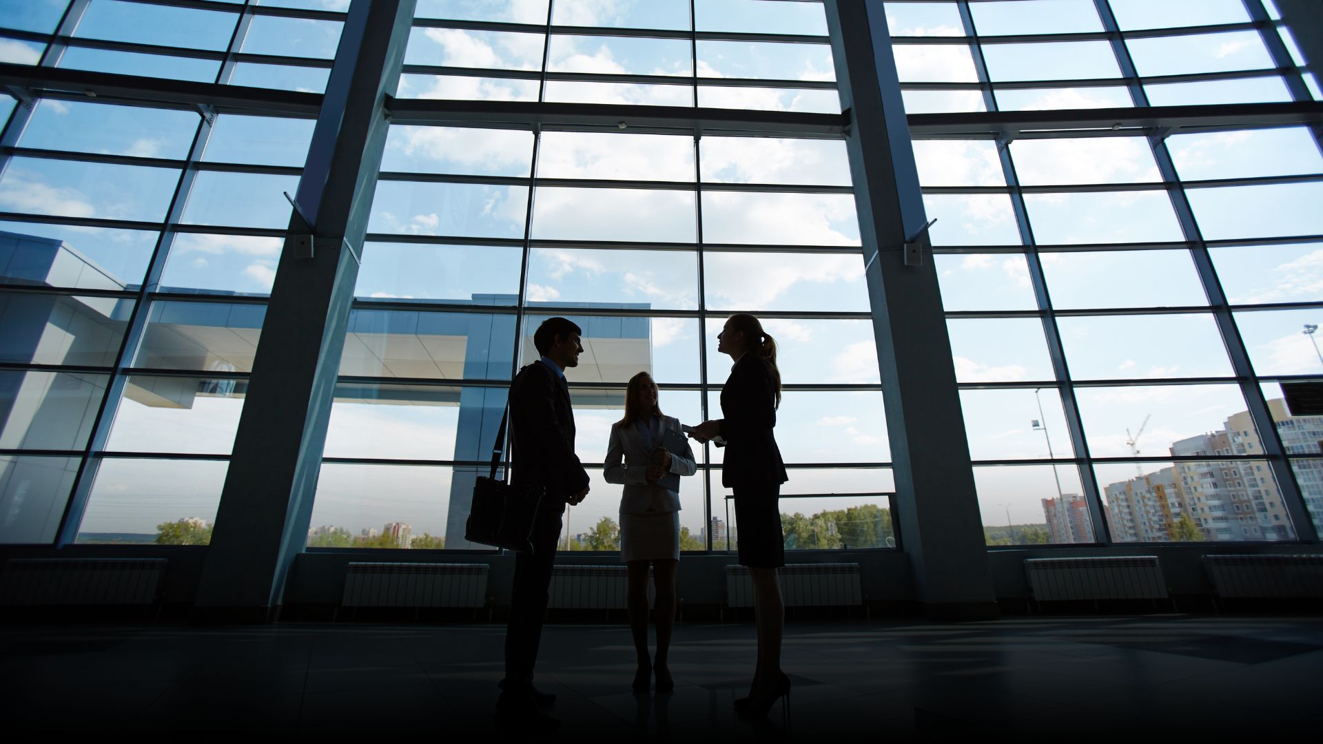 Three professionals engaged in a discussion by windows